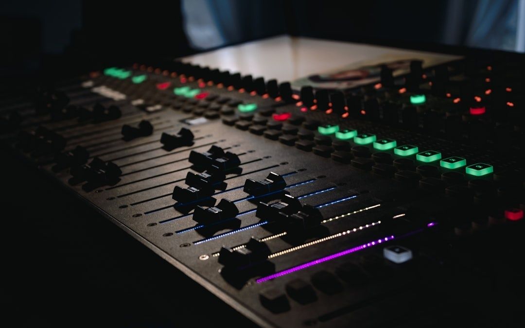 Audiomengpaneel met faders en kleurrijke verlichte knoppen in een donkere studio